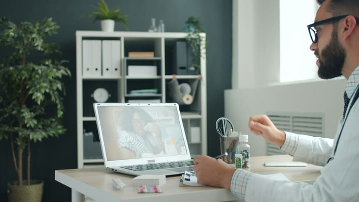 Médico em consulta por videochamada com uma paciente, pelo notebook.