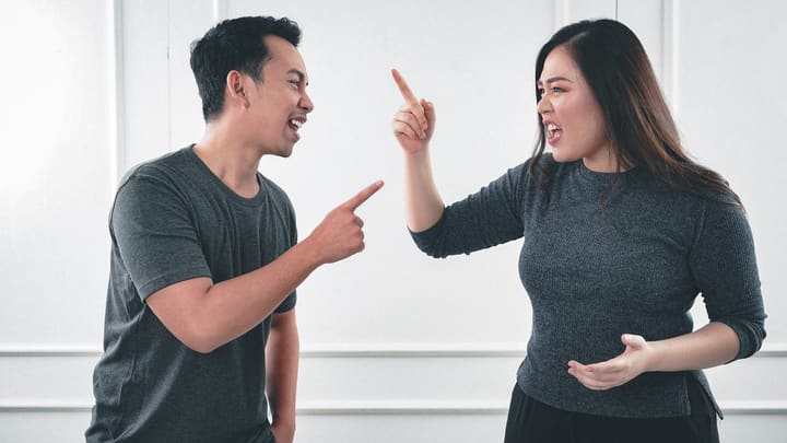 Um homem e uma mulher discutindo, apontando o dedo um para o outro.
