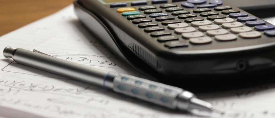 Calculadora gráfica e lapiseira sobre folhas com anotações.