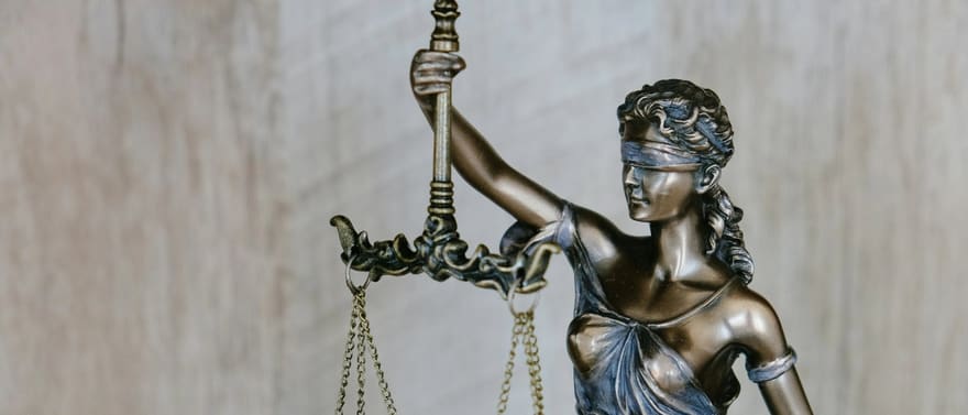 Estátua da Justiça vendada, segurando a balança e a espada.