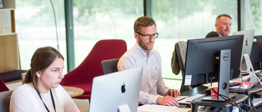 Pessoas trabalhando em computadores em um escritório.